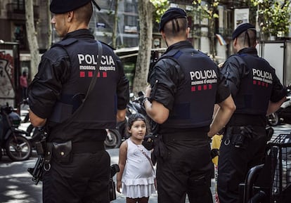 Una niña mira a una pareja de Mossos en La Rambla.