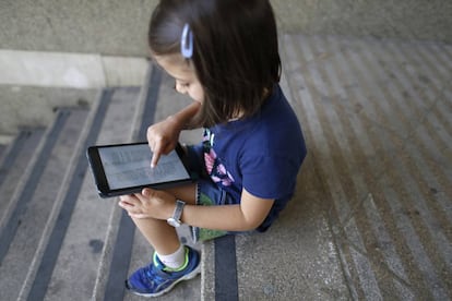 Una niña lee un libro en una tableta.