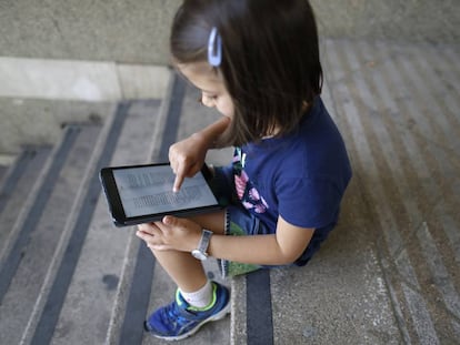 Una niña lee un libro en una tableta.