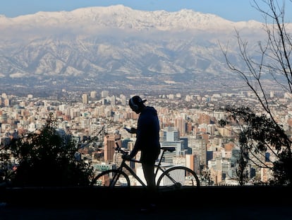 Un hombre en bicicleta revisa su teléfono móvil en la Colina de San Cristóbal, en Santiago de Chile.