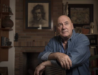 Juan Erasmo posa en el salón de su casa junto a un retrato de juventud.