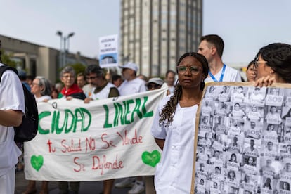 Una mujer sostiene un cartel con las caras de sanitarios, durante la concentración de los trabajadores del Hospital Universitario de La Paz.