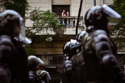 Una persona observa a los policías desde un balcón.