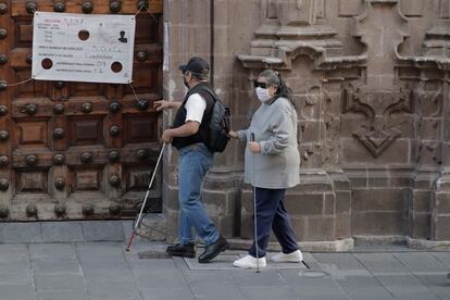 Dos personas ciegas caminan por el centro histórico de la Ciudad de México.