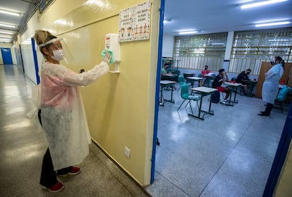 Mãe de aluno, contratada em um programa de temporários da Prefeitura, desinfeta um recipiente de álcool gel na escola de ensino fundamental Sylvia Martin Pires em São Paulo, em 8 de março de 2021.