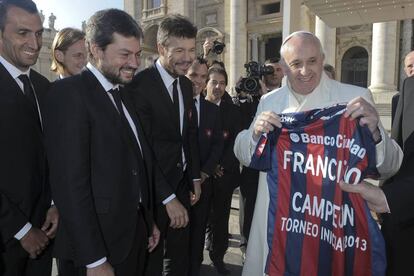 El Papa Francisco sujeta la camiseta del club de fútbol argentino San Lorenzo, que le han regalado los miembros del equipo durante la audiencia en la Plaza de San Pedro del Vaticano, el 18 de diciembre de 2013.