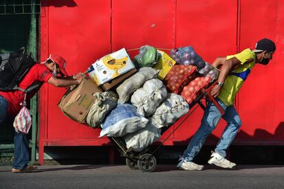 Dos hombres llevan un carro cargado de comida en una calle de Tegucigalpa después de que el Gobierno anunciara la reanudación de la actividad económica, en medio de la pandemia de covid-19. Honduras reabre sus actividades comerciales, con cautela, después de casi tres meses de encierro.