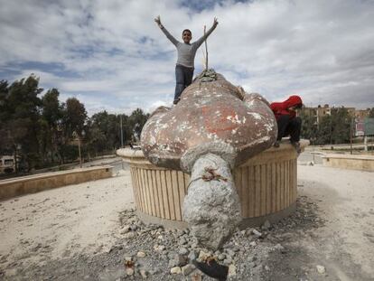 Unos ni&ntilde;os juegan en Raqqa con los restos de una estatua de Basil El Asad, hermano del presidente.