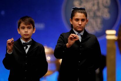 Los niños del colegio de San ildefonso Luis Alcides y Nerea Pareja muestran las bolas con el número 41.710, primero de los dos cuartos premios, esta mañana en Madrid.