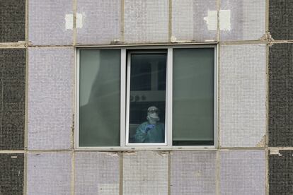 Un médico de UCI en el Hospital La Paz, en Madrid, a través de una ventana.