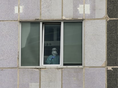 Un médico de UCI en el Hospital La Paz, en Madrid, a través de una ventana.