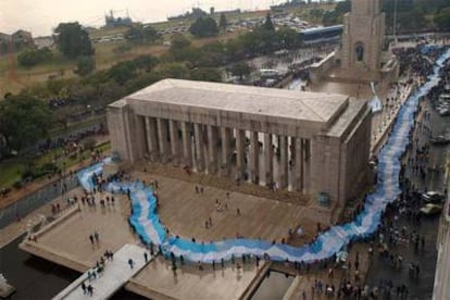 Cientos de personas rodean el Monumento a la Bandera en Rosario con una bandera de mas de 9.000 metros confeccionada con telas procedentes de distintas partes de Argentina durante el Dia de la Bandera celebrado en junio.