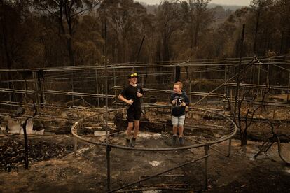 <p>Niños entre los restos de una cama elástica quemada en Conjola Park.</p> _ <p>Australia vive un infierno sin precedentes estas semanas. Aunque los incendios forestales son frecuentes durante el verano austral, los que arrasan desde noviembre parte de los Estados de Nueva Gales del Sur y Victoria son de los más feroces, devastadores y letales que se recuerdan. A principios de enero habían consumido más de 10 millones de hectáreas de superficie, destruido 2 millares de edificios y matado al menos a 28 personas (con muchos más desaparecidos), además de causar daños descomunales en la fauna. Decenas de miles de personas se han visto obligadas a abandonar sus hogares según avanzaban las columnas de fuego y acorralaban núcleos rurales. Las nubes tóxicas amenazan la calidad del aire en grandes ciudades como Sídney o Melbourne, donde se tuvieron que suspender los entrenamientos para el Open de Australia por el alto nivel de partículas dañinas para la salud suspendidas en el aire. En medio del debate global y nacional sobre el cambio climático —y tras una de las peores sequías en décadas y temperaturas máximas en diciembre—, los incendios forestales han adquirido dimensiones bélicas. Son muchos quienes expresan su preocupación estos días, ya que aún queda por delante otro mes caluroso: febrero. </p>