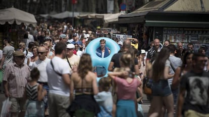 Un turista con flotador y toalla al hombro baja por las Ramblas.