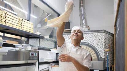 Un cocinero voltea una masa de pizza en el aire en un restaurante de Roma.