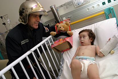 Un bombero entrega un regalo a una niña ingresada en el hospital Gregorio Marañón.