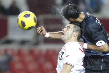 Malagueño disputa la pelota con Negredo.