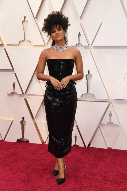 A atriz Zazie Beetz, conhecida por seus papéis na série 'Atlanta' ou em filmes como 'Lucy in the Sky', desfila pelo tapete vermelho do Oscar 2020 com um vestido preto brilhante, assinado por Thom Browe.