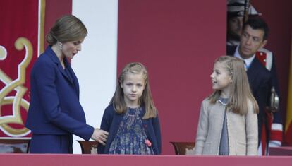La Reina, pendiente en todo momento de sus dos hijas, les indica a la princesa Leonor y a la infanta Sofía cómo colocarse en la tribuna.