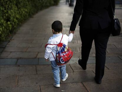 Un ni&ntilde;o con su mochila camina de la mano de su madre camino del colegio p&uacute;blico Reina Victoria de Madrid.