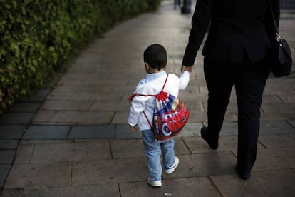 Un ni&ntilde;o con su mochila camina de la mano de su madre camino del colegio p&uacute;blico Reina Victoria de Madrid.