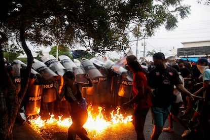 Manifestantes reaccionan cuando cócteles molotov golpean el suelo frente a las fuerzas de seguridad durante las protestas contra los resultados electorales.