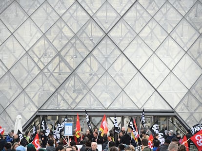 Algunos empleados sujetan pancartas y banderas de sindicatos mientras bloquean la entrada Louvre para denunciar la controvertida reforma de las pensiones del Gobierno, este lunes en París.