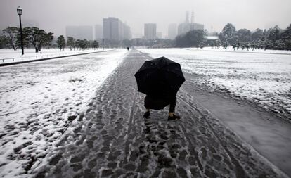 Un hombre, agachado para tocar la nieve, en una calle en las cercanías del Palacio Imperial de Tokio.