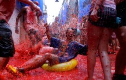 Un turista asiático se desliza con un flotador sobre un río de tomates.