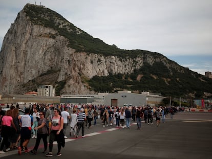 Peatones cruzan la pista en el aeropuerto de Gibraltar, con el peñón al fondo.