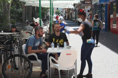 Una camarera atiende a los clientes de una terraza del distrito madrileño Puente de Vallecas.