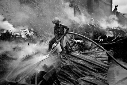 Zona de Procesamiento de Exportaciones. Un bombero intenta apagar el incendio en una fábrica textil en Dacca, Bangladesh, en agosto de 2005. Las condiciones inseguras de trabajo han hecho que la tragedia se repita.