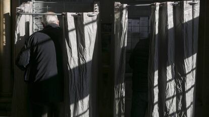 Dos votantes escogen sus papeletas en una cabina durante las elecciones en Cataluña de 2017.