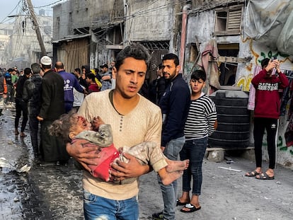 Un hombre lleva en brazos a una niña víctima de un bombardeo en Rafah, en el sur de la franja de Gaza, el 1 de diciembre.