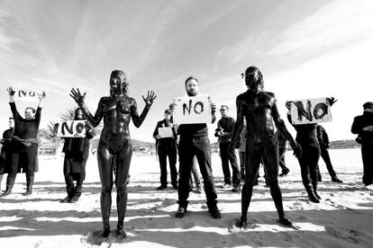 Performance contra las prospecciones petrolíferas en las costas de Baleares y golfo de Valencia. Momento de la protesta en la que posan juntos los participantes desnudos y cubiertos de petróleo y otros voluntarios vestidos de negro y con carteles reivindicativos que guardaron silencio durante el acto en la playa de Talamanca, Ibiza.