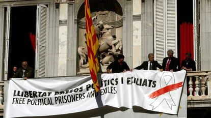 Trabajadores de la Generalitat colocan una pancarta con un lazo blanco encima de la que había antes.