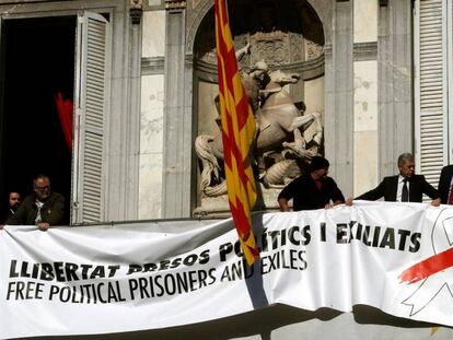 Trabajadores de la Generalitat colocan una pancarta con un lazo blanco encima de la que había antes.