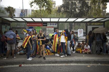 Varios estudiantes se protegen de la lluvia en una parada de bus durante la protesta de estudiantes ante la sede de la Universidad de Barcelona a favor de la celebración del referéndum del 1 de octubre.