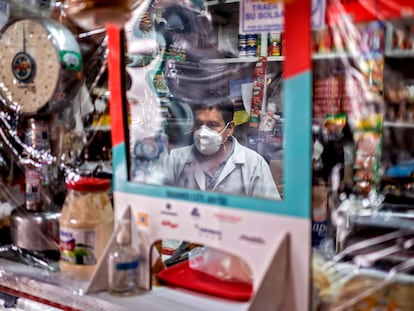 Un vendedor atiende espera clientes detrás de un plástico protector, durante la pandemia de covid en Ciudad de México.