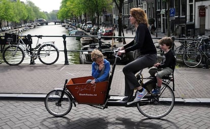 Una madre con sus hijos cruzando en bici uno de los canales de Ámsterdam.