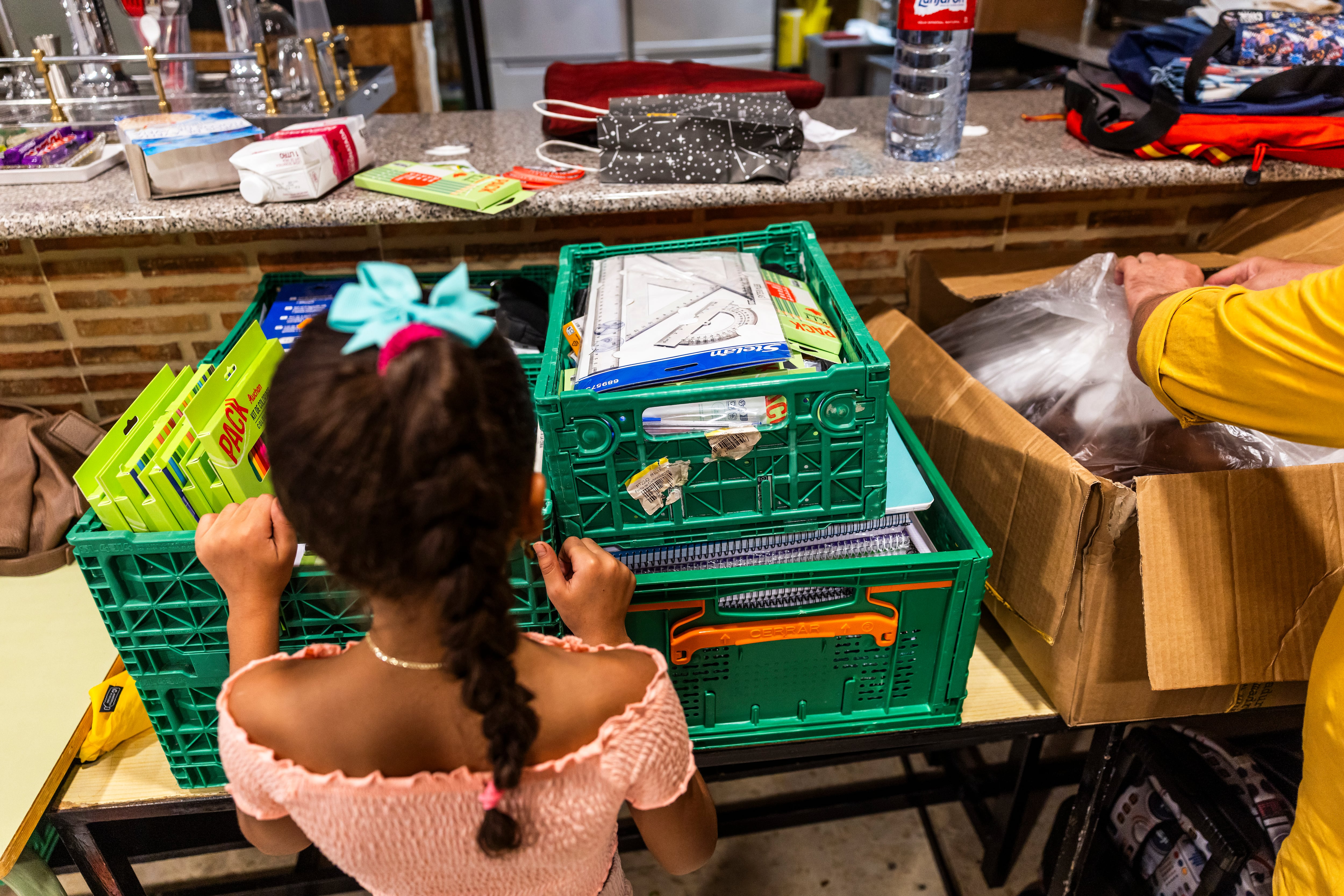 Una niña de El Pozo mira el material escolar recogido en la Asociación Vecinal Red Entrepozo de Vallecas, para donar a las familias del barrio que no puedne permitírselo.