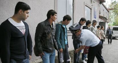 Un policía cachea a varios inmigrantes en una redada a las afueras de Moscú.