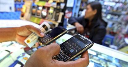 Un cliente sostiene dos tel&eacute;fonos m&oacute;viles BlackBerry en una tienda de un centro comercial.