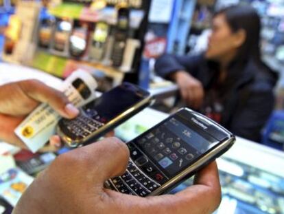 Un cliente sostiene dos tel&eacute;fonos m&oacute;viles BlackBerry en una tienda de un centro comercial.