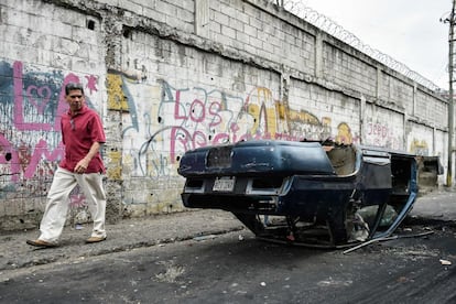 Un hombre camina junto a un coche volcado durante las protestas del martes por la noche en Caracas.