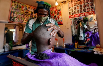 Un barbero protegido con mascarilla afeita a un cliente, en Nairobi (Kenya).