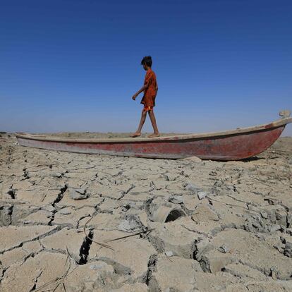 -- AFP ENVIRONMENT PICTURES OF THE YEAR 2022 -- 

A boy walks on a boat left lying on the dried-up bed of a section of Iraq's receding southern marshes of Chibayish in Dhi Qar province, on June 28, 2022. - Iraq's drought reflects a decline in the level of waterways due to the lack of rain and lower flows from upstream neighboring countries Iran and Turkey. (Photo by Asaad NIAZI / AFP) / AFP ENVIRONMENT PICTURES OF THE YEAR 2022