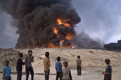 Varios niños observan un pozo de petróleo quemándose, en Qayyarah (Irak).