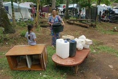 Lenizahara mira cómo su madre Trisnawati reúne sus pertenencias en un campo de desplazados de Banda Aceh.