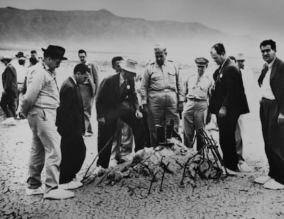 Robert Oppenheimer (wearing hat and suit), General Leslie Groves and other scientists and military personnel examine the ruins of a tower leveled by the first atomic bomb test in New Mexico.